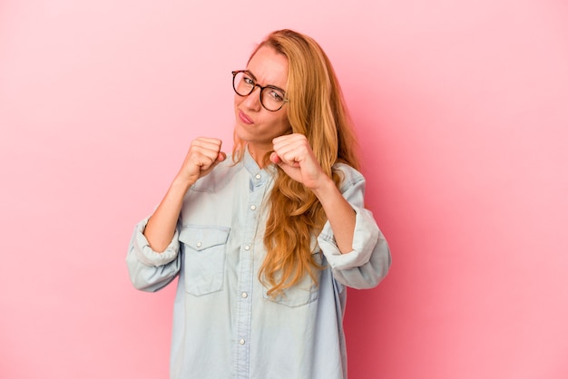 Donna bionda caucasica isolata su sfondo rosa che lancia un pugno, rabbia, combattimento a causa di una discussione, boxe.