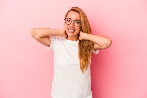 Donna bionda caucasica isolata su sfondo rosa che tocca la parte posteriore della testa, pensa e fa una scelta.