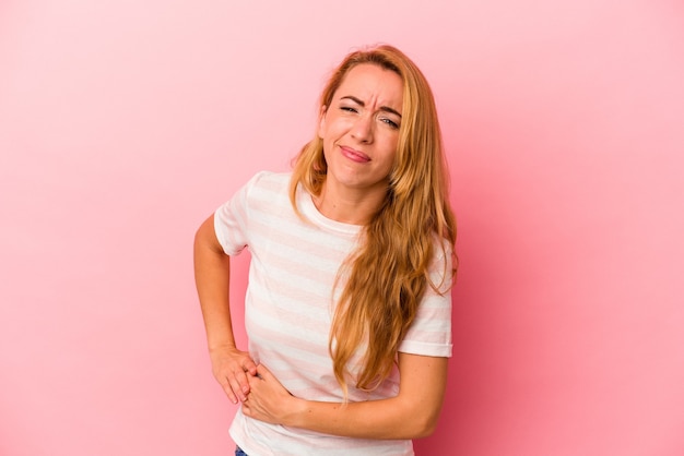 Donna bionda caucasica isolata su sfondo rosa con dolore al fegato, mal di stomaco.