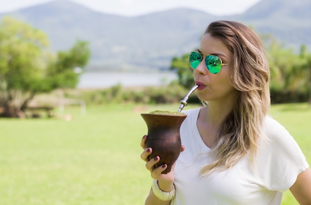 Donna bionda che beve il tradizionale Chimarrao dallo Stato di Rio Grande do Sul in Brasile.