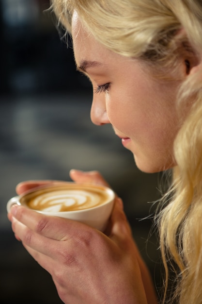 Donna bionda che beve una tazza di caffè