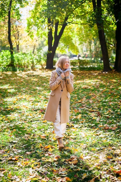 Donna bionda che cammina nel parco autunnale