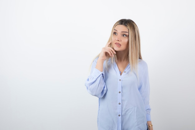 Donna bionda che guarda l'obbiettivo sul muro bianco