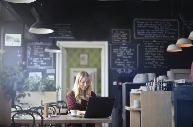 Donna bionda che lavora da una caffetteria