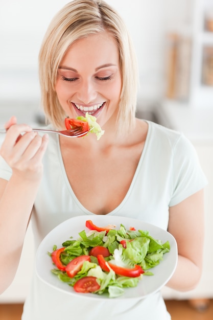 Donna bionda che mangia insalata