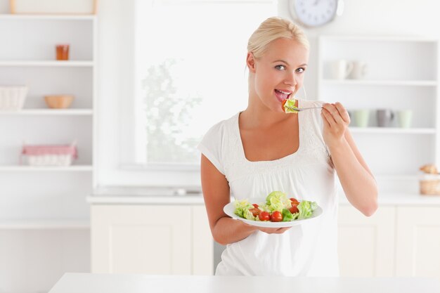 Donna bionda che mangia insalata