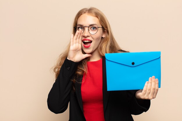 Donna bionda che si sente felice, eccitata e positiva, gridando con le mani vicino alla bocca, chiamando