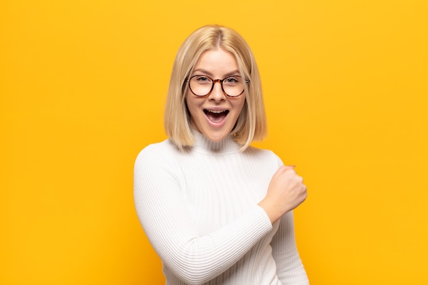 Donna bionda che si sente felice, positiva e di successo, motivata quando affronta una sfida o celebra buoni risultati