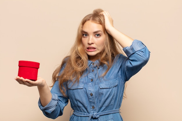 Donna bionda che si sente stressata, preoccupata, ansiosa o spaventata, con le mani sulla testa, in preda al panico per errore