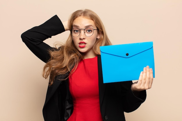 Donna bionda che si sente stressata, preoccupata, ansiosa o spaventata, con le mani sulla testa, in preda al panico per l'errore