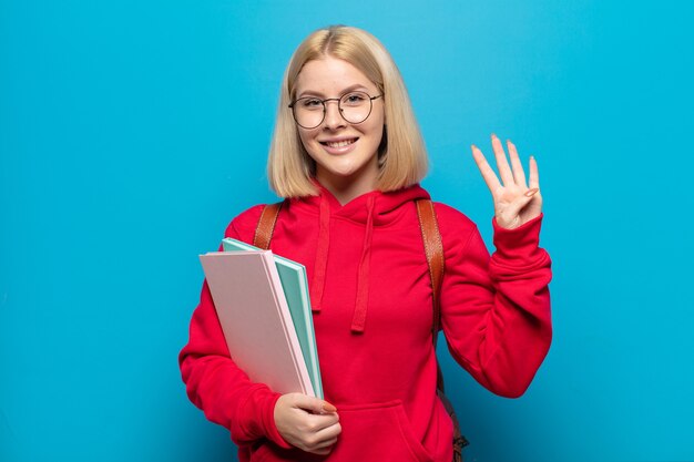 Donna bionda che sorride e sembra amichevole, mostrando il numero quattro o quarto con la mano in avanti, conto alla rovescia