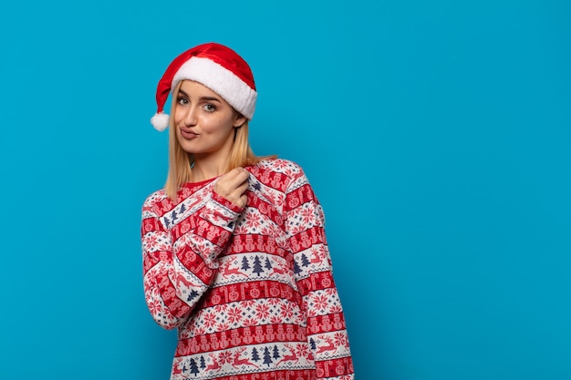 Donna bionda con cappello da Babbo Natale che sembra arrogante, di successo, positiva e orgogliosa, indicando se stessa