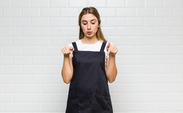 Donna bionda con la bocca aperta rivolta verso il basso con entrambe le mani, che sembra scioccata, stupita e sorpresa