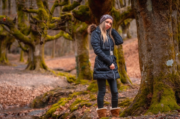 donna bionda con un lungo cappotto in una foresta