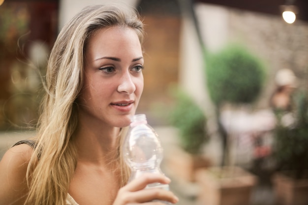 Donna bionda con una bottiglia di plastica