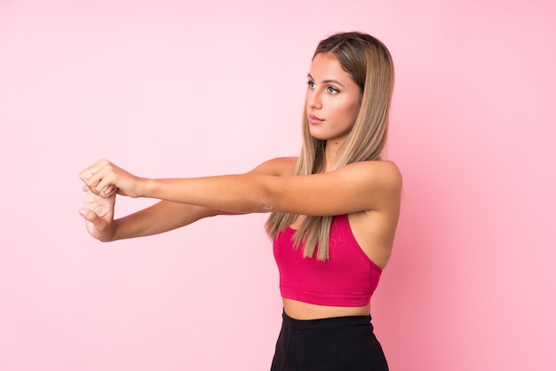 Donna bionda di giovane sport sopra l'allungamento rosa isolato