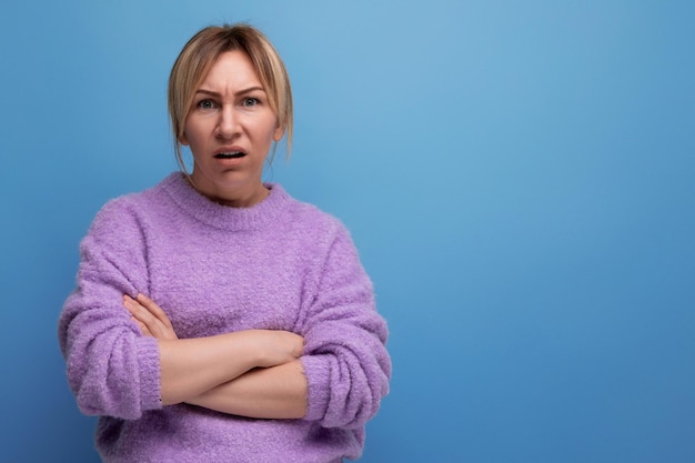 Donna bionda dubbiosa che guarda con disprezzo la macchina fotografica su sfondo blu con spazio di copia