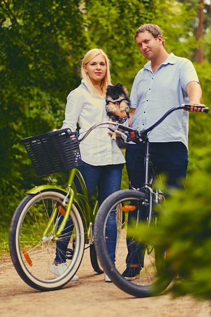 Donna bionda e un uomo in bicicletta in un parco.