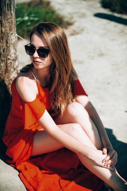 Donna bionda elegante con il vestito rosso sulla spiaggia