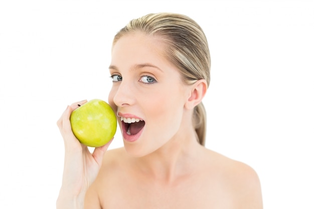 Donna bionda fresca adorabile che mangia una mela verde