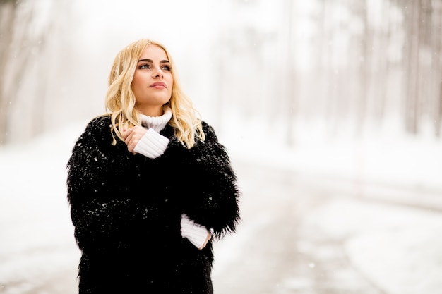 Donna bionda fuori in cappotto di neve invernale