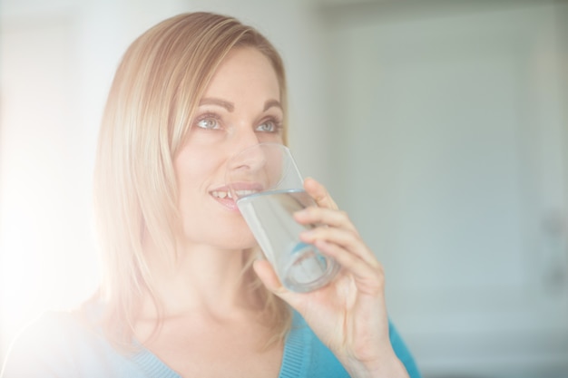 Donna bionda graziosa che beve un bicchiere d'acqua