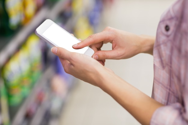 Donna bionda graziosa che usando il suo smartphone