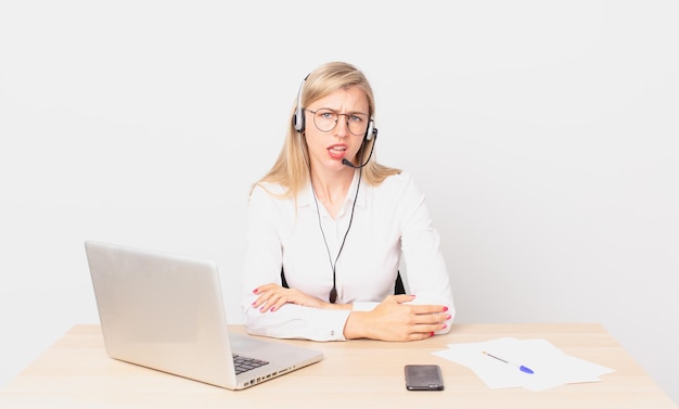 Donna bionda graziosa giovane donna bionda che si sente perplessa e confusa e lavora con un laptop