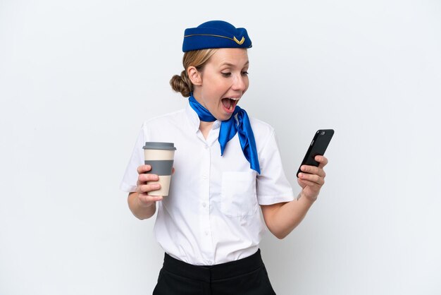 Donna bionda hostess dell'aeroplano isolata su sfondo bianco che tiene il caffè da portare via e un cellulare