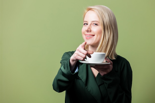 Donna bionda in mantello con una tazza di caffè