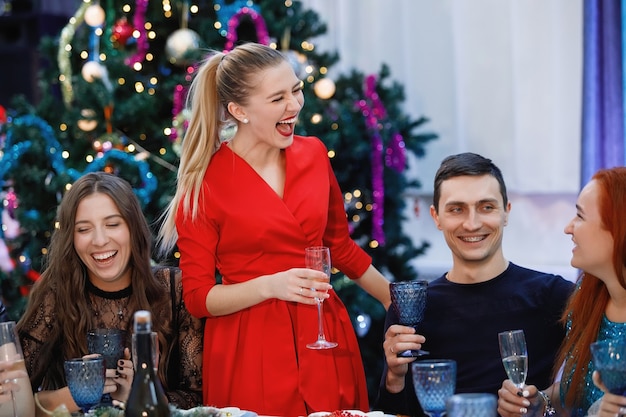 Donna bionda in rosso brinda agli amici a tavola a Natale e Capodanno.