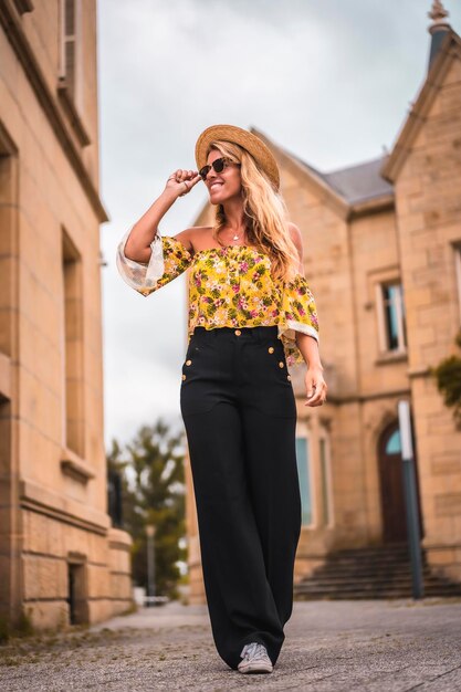 Donna bionda in un abito vintage giallo con un cappello che visita un castello