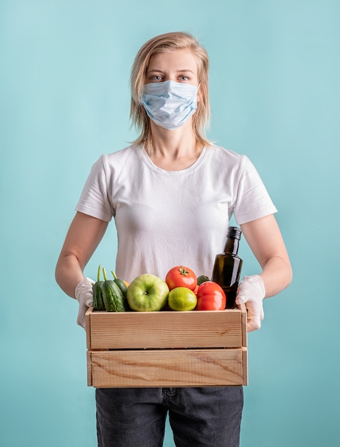 Donna bionda in una maschera e guanti che tengono una scatola di legno