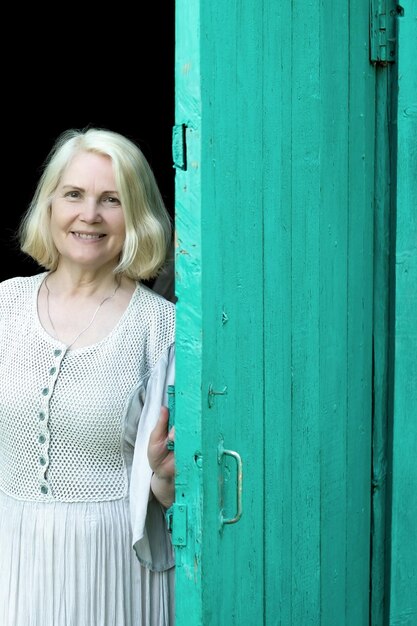 Donna bionda in vestito che apre la porta d'ingresso della casa