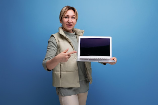 Donna bionda millenaria che mostra lo schermo del laptop con il mockup della pagina