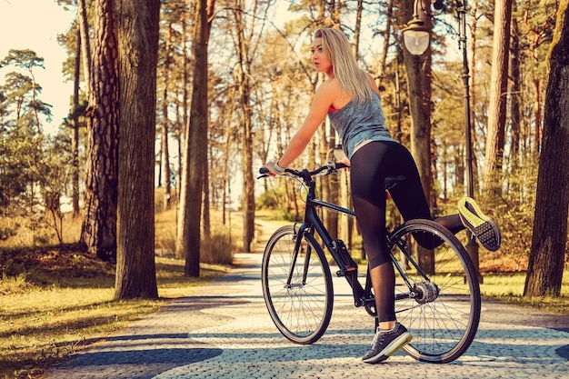 Donna bionda sexy su una bicicletta in un parco estivo