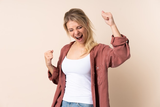 Donna bionda sopra la parete isolata che celebra una vittoria