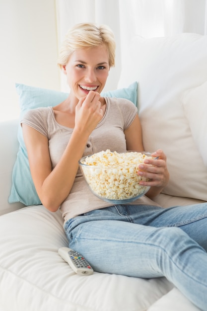 Donna bionda sorridente del ritratto che mangia pop corn