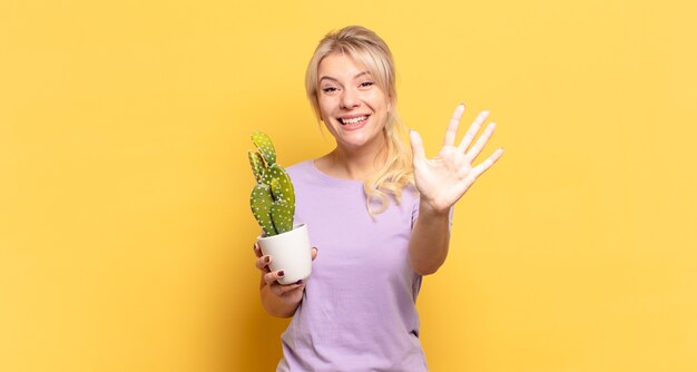 Donna bionda sorridente e dall'aspetto amichevole, che mostra il numero cinque o il quinto con la mano in avanti, conto alla rovescia