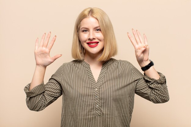 Donna bionda sorridente e dall'aspetto amichevole, mostrando il numero nove o nono con la mano in avanti, conto alla rovescia