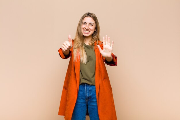 Donna bionda sorridente e guardando amichevole, mostrando il numero sei o sesto con la mano in avanti, conto alla rovescia