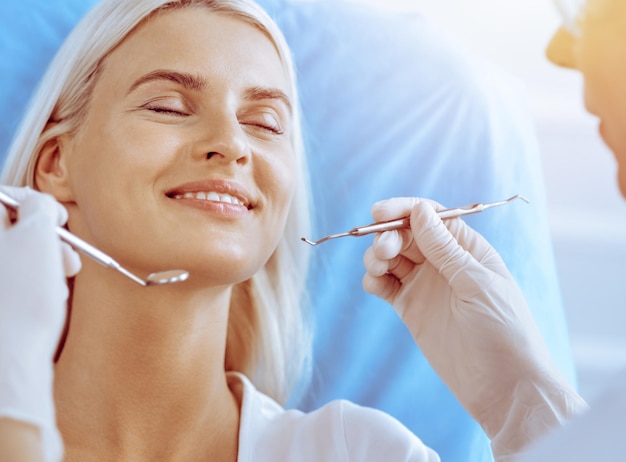 Donna bionda sorridente esaminata dal dentista presso la clinica dentale Denti sani nel concetto di medicina