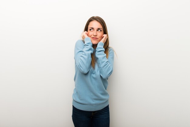 Donna bionda su sfondo bianco isolato che coprono le orecchie con le mani. Espressione frustrata