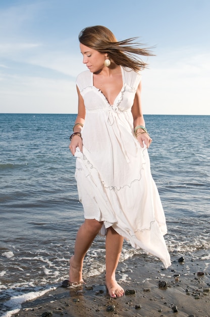 donna bionda vestita di bianco che si gode la tranquillità della riva del mare