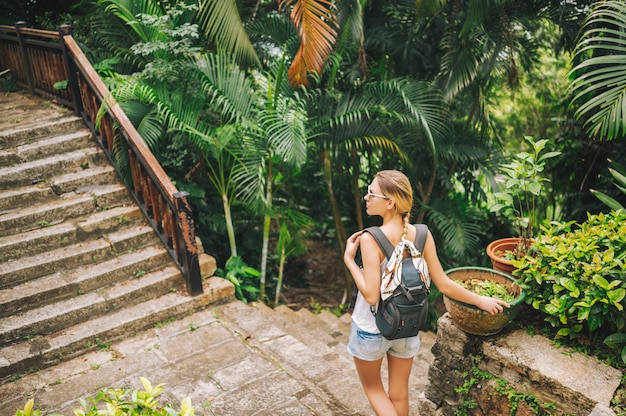 Donna bionda viaggiatore con zaino e sacco a pelo che cammina e che scopre il parco tropicale della giungla, natura di avventura di viaggio in Cina, bella destinazione turistica Asia, concetto di viaggio di viaggio di vacanze estive di vacanza