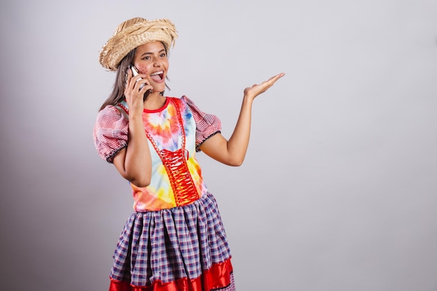 Donna brasiliana che indossa abiti country Festa di Sao Joao Festa di Junina Con lo smartphone in chiamata vocale