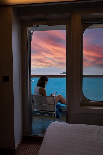 Donna brasiliana di 42 anni sul balcone della cabina di crociera che interagisce con il suo smartphone_verti