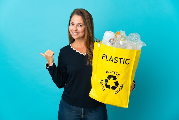 Donna brasiliana di mezza età che tiene un sacchetto pieno di bottiglie di plastica da riciclare