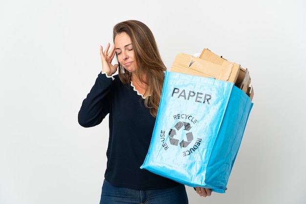 Donna brasiliana di mezza età che tiene una borsa per il riciclaggio piena di carta da riciclare isolata con mal di testa