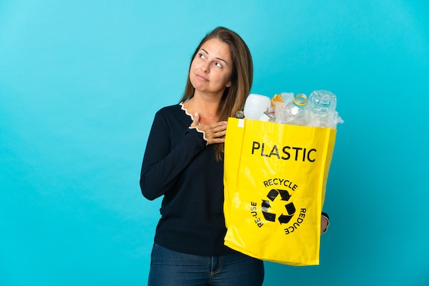 Donna brasiliana di mezza età che tiene una borsa piena di bottiglie di plastica da riciclare